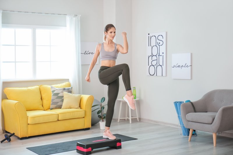 A young woman doing aerobics in her home gym with inspirational wall art (Photo by Pixel-Shot - stock.adobe.com)